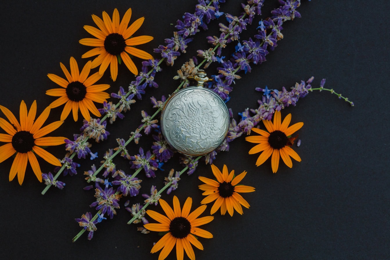 Analog pocket watch surrounded by flowers