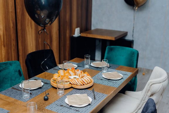 Table à manger dressée pour un petit-déjeuner avec une assiette avec des sandwichs, des verres, des couverts et une décoration de ballons