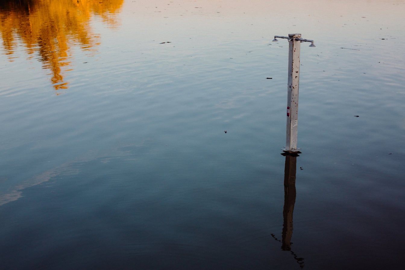 Metalen paal van een buitendouche overstroomd in het water