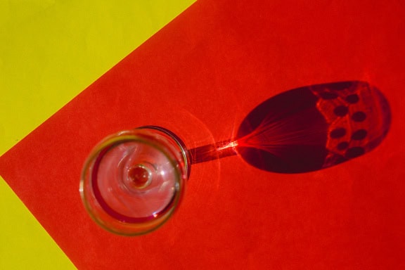 A crystal glass with shadow on a yellow-dark red two-tone background