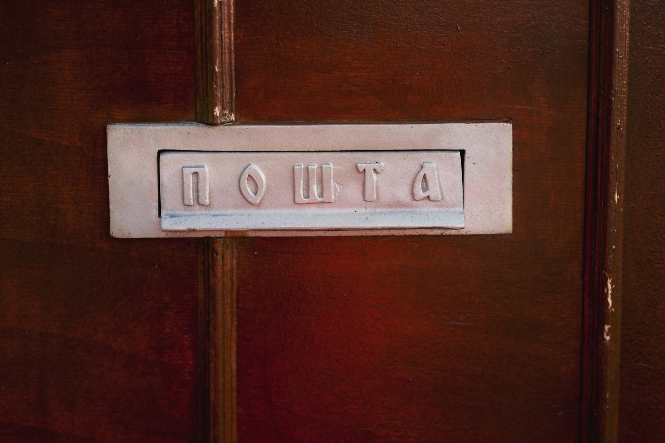 A mailbox with a mail slot on a door with  text inscription in Serbian Cyrillic letters