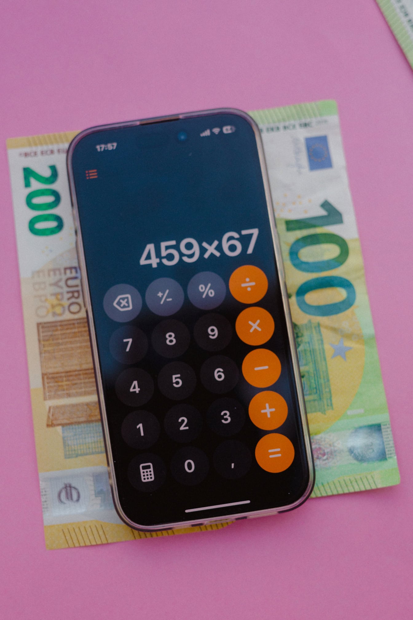 Een mobiele telefoon met een rekenapplicatie op papieren bankbiljetten van tweehonderd (€200) en honderd euro (€100)