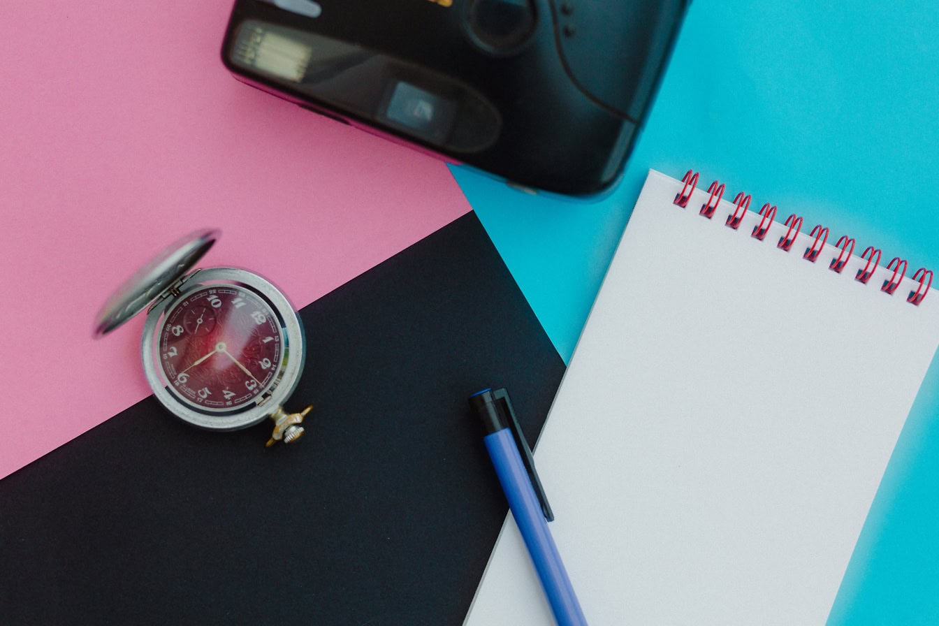 Une vieille montre de poche de l’Union soviétique ou de l’URSS, un stylo sur un cahier et un appareil photo analogique