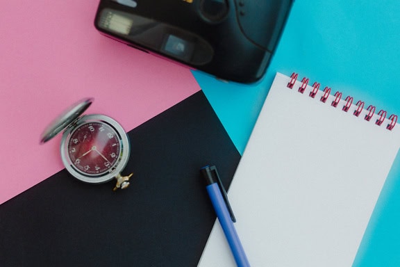 Eine alte Taschenuhr aus der Sowjetunion oder der UdSSR, ein Stift auf einem Notizbuch und eine analoge Fotokamera