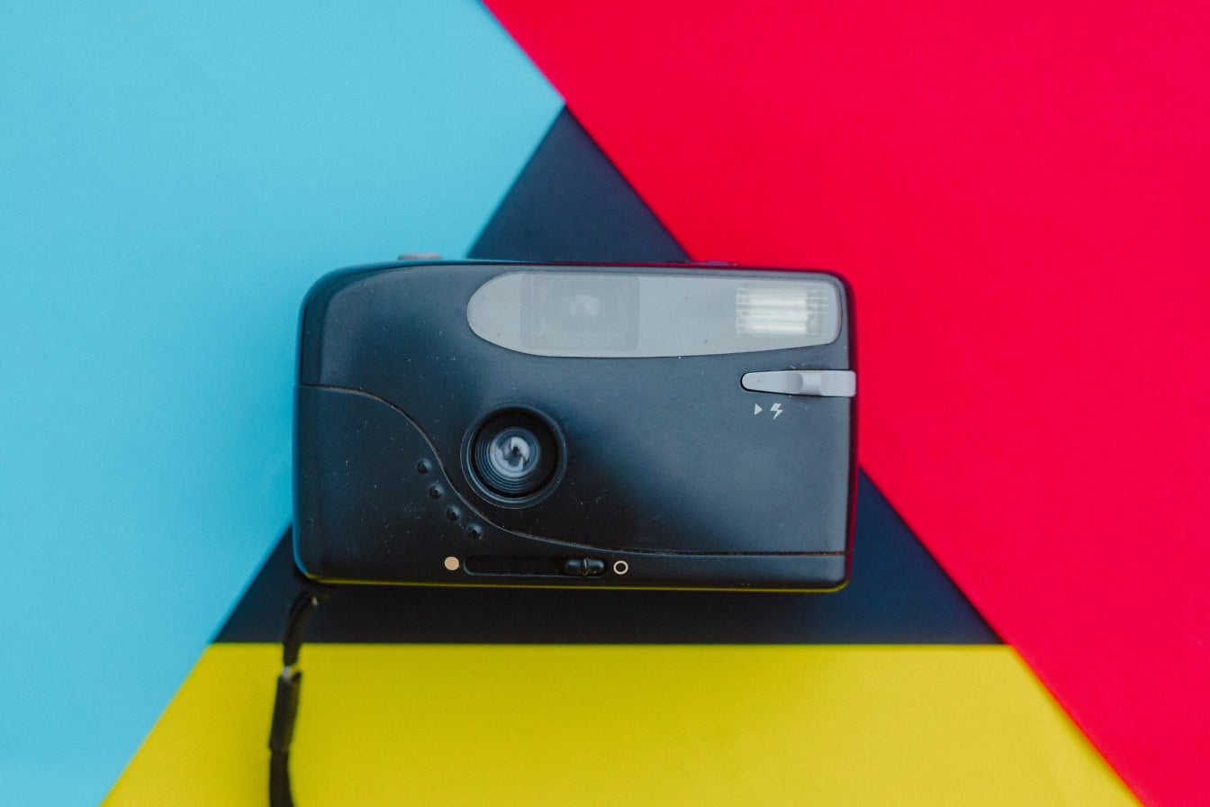 Old plastic black camera on a multicolored background