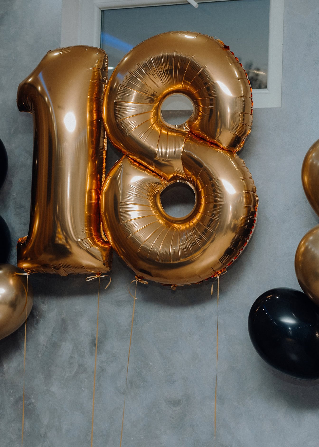 Gold and bronze-brown balloons filled with helium in the shape of the number 18, birthday decoration to celebrate eighteenth birthdays and adulthood