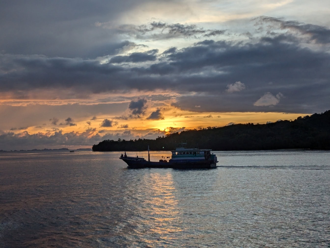 Silhouette of a fishing boat on sea at sunrise