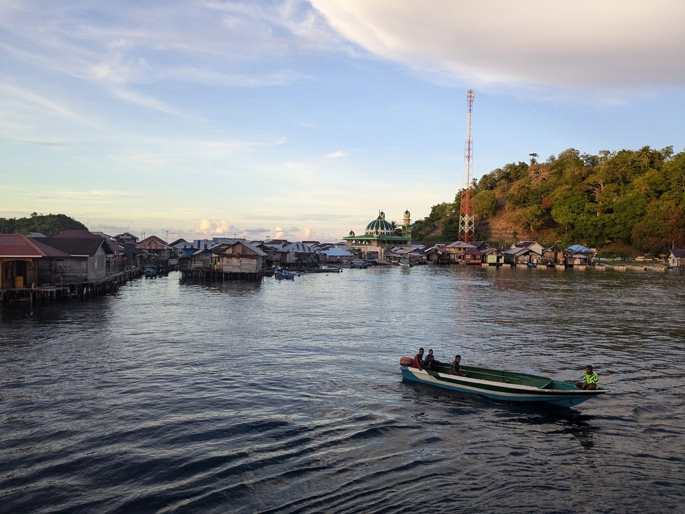 Um barco a motor na água com uma vila aquática com casas flutuantes em um bairro pobre