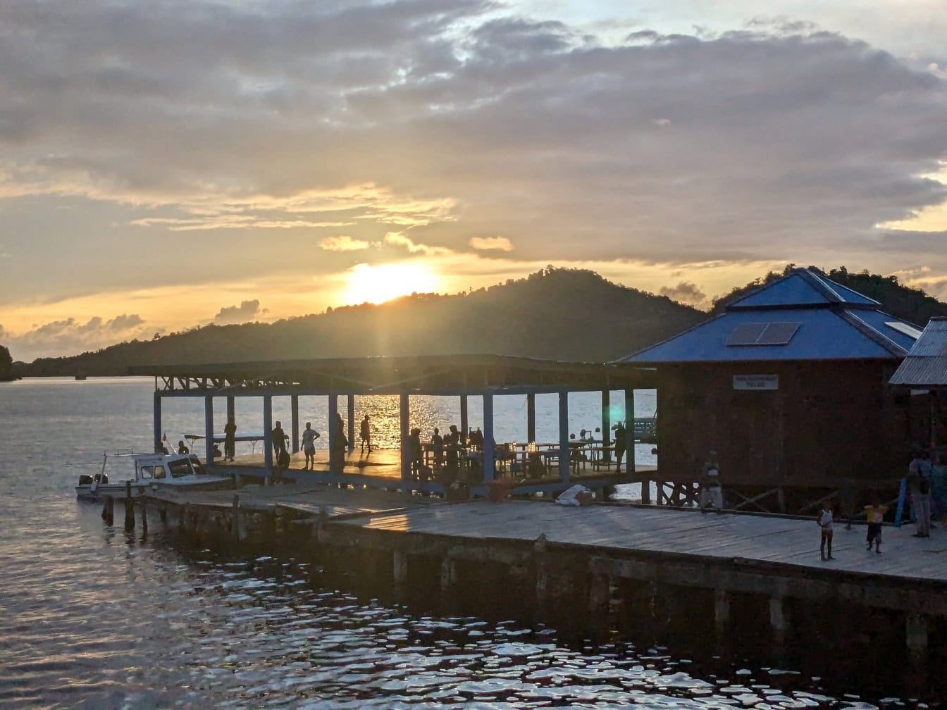 Group of people on a dock with boathouses at sunset