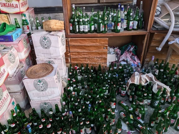 A warehouse of a store with many empty bottles on the floor next to boxes on beer