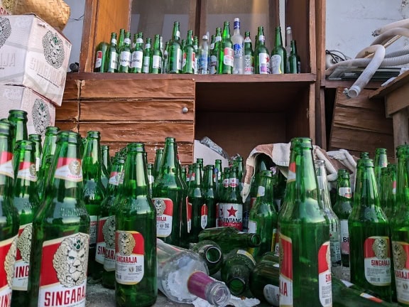 A warehouse with many green empty bottles of beer on floor