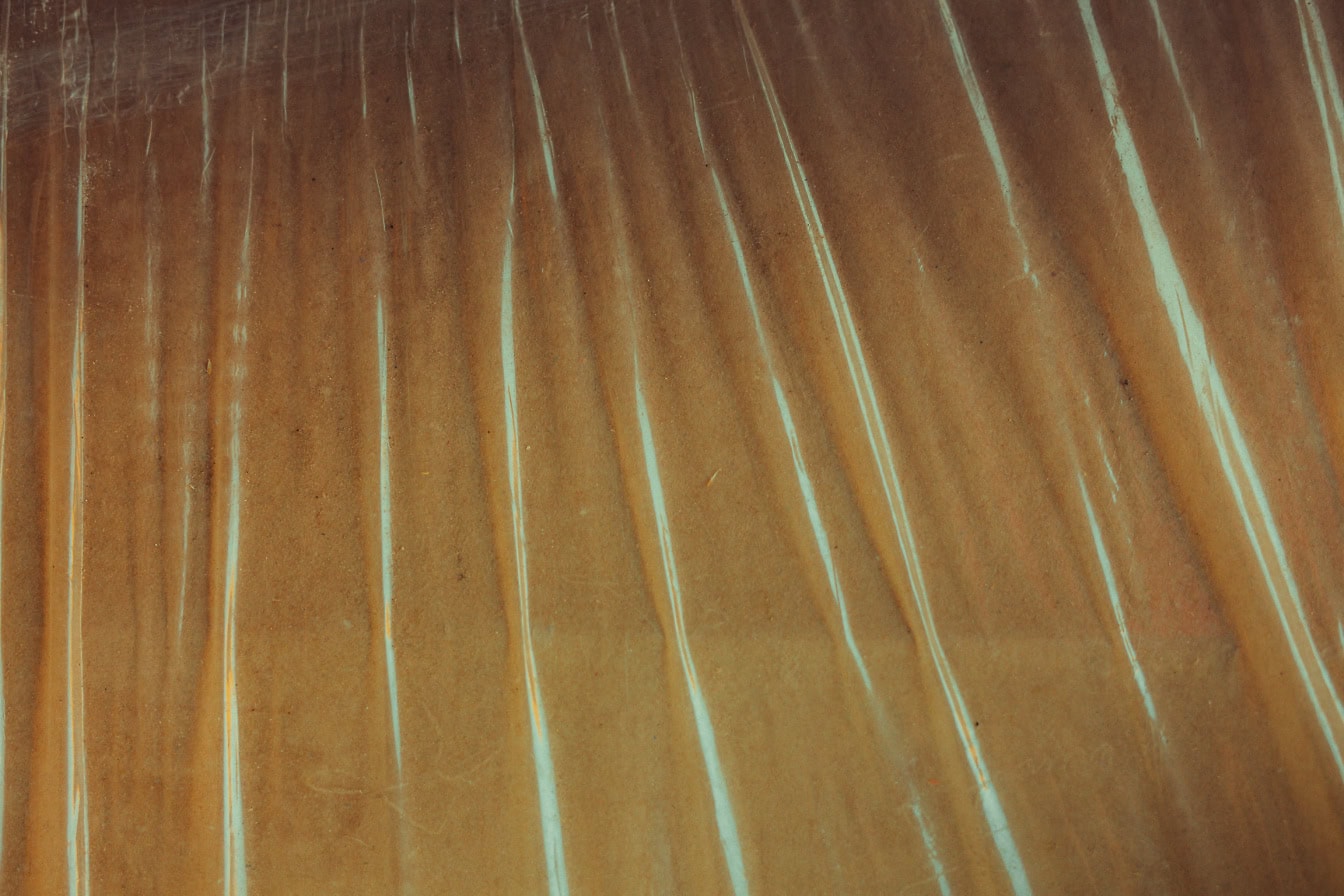 Texture of a shining transparent nylon stretched over brown carton surface