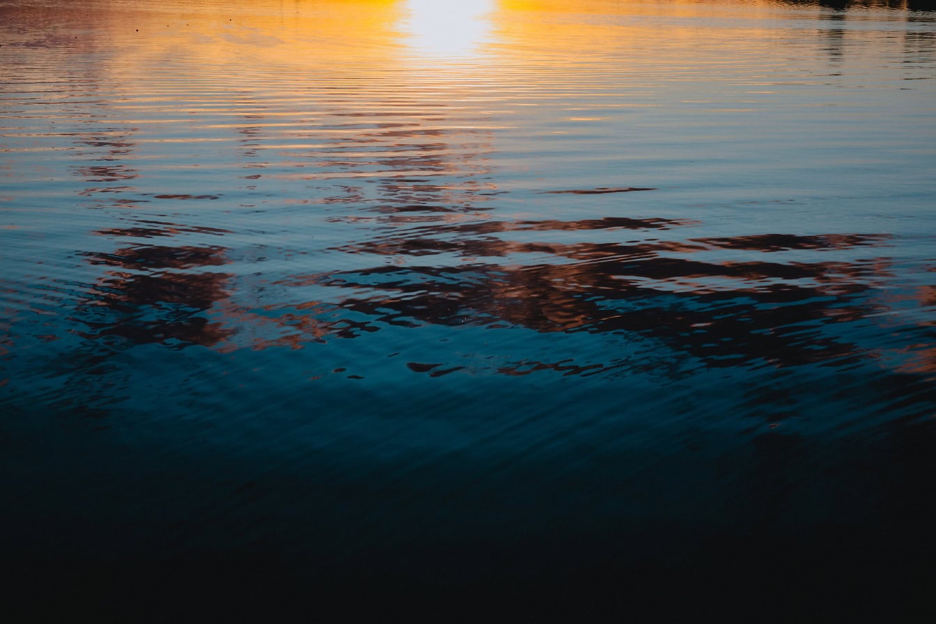 Landscape at early sunrise on river with sunrays reflecting off water