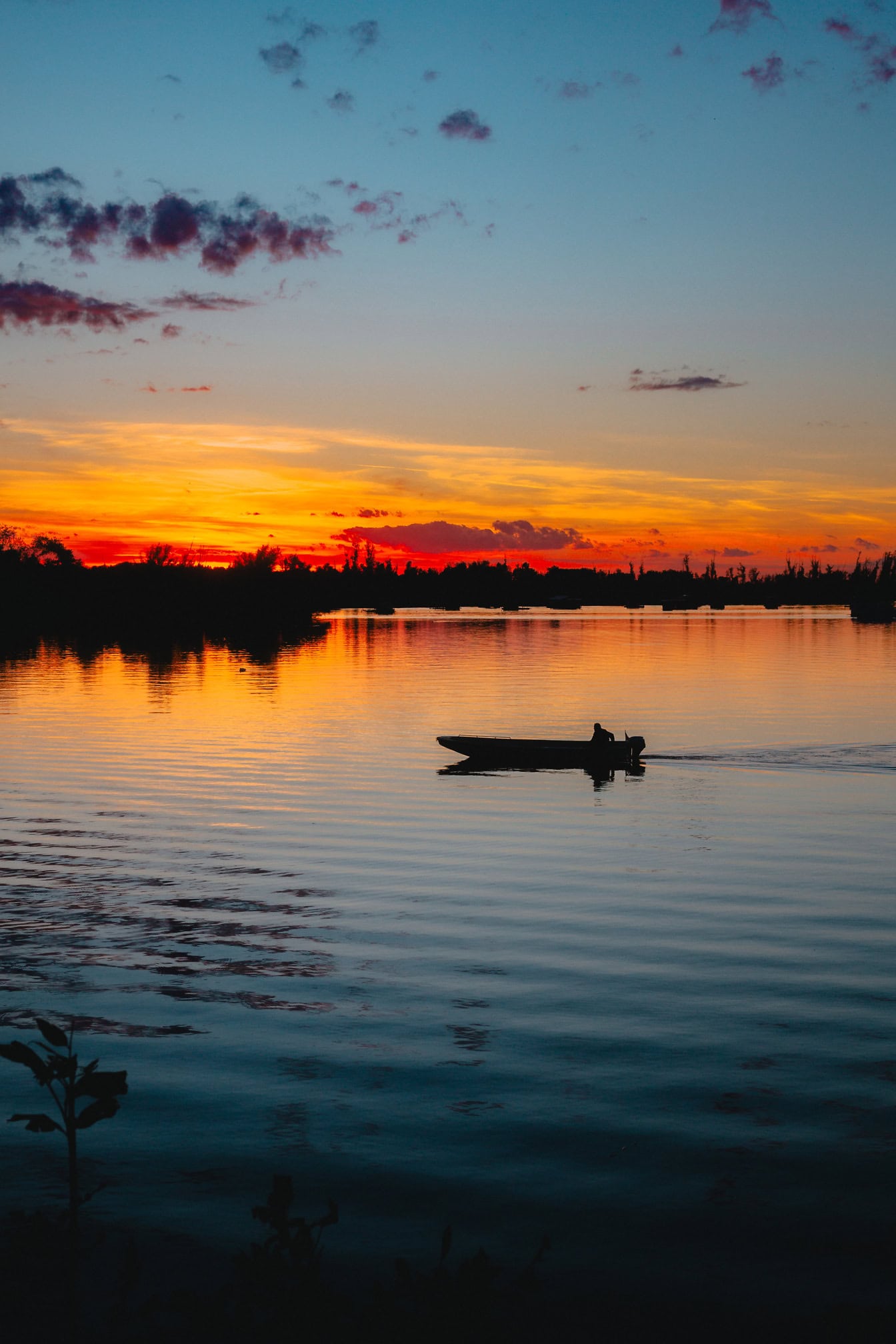 ティクヴァラ自然公園、バチュカ・パランカの夕暮れ時の水面に映る鮮やかなオレンジレッドの空を持つ小さなボートのシルエット