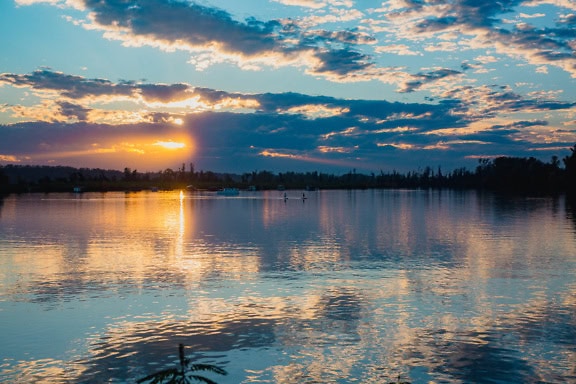 Schemering over een meerkant met reflectie van wolken op water