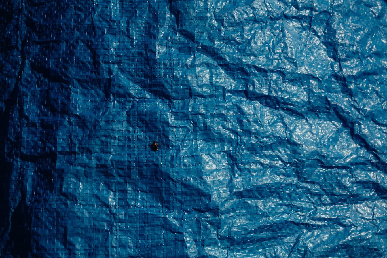 Dunkelblaue Nylonplane, Textur der zerknitterten Oberfläche einer Folie aus Polyvinylchlorid (PVC), einem synthetischen Polymer aus Kunststoff