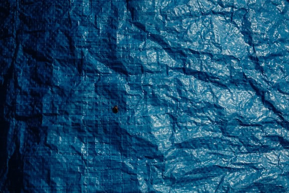 Dunkelblaue Nylonplane, Textur der zerknitterten Oberfläche einer Folie aus Polyvinylchlorid (PVC), einem synthetischen Polymer aus Kunststoff