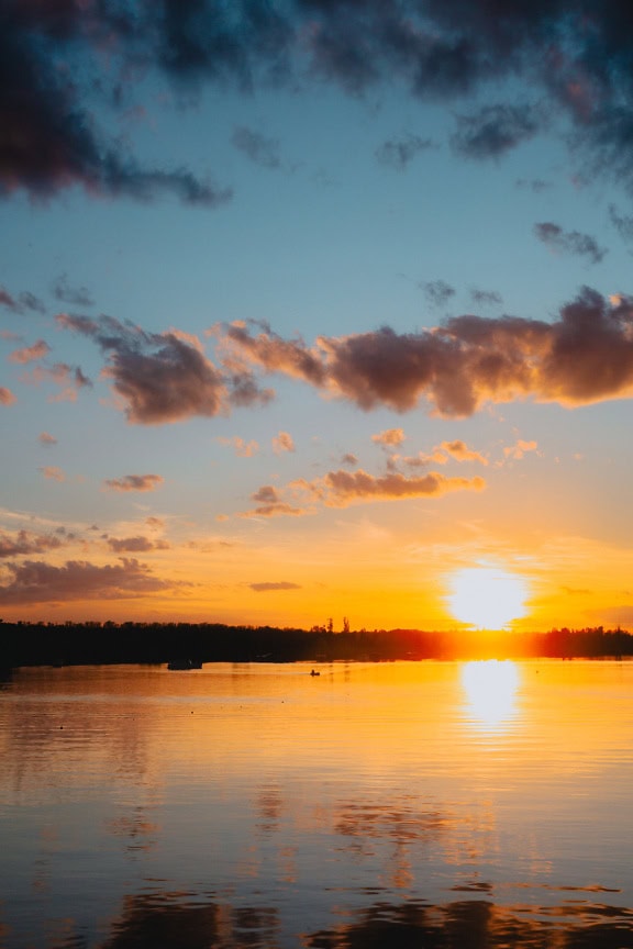 Dramaattinen auringonlasku kirkkaalla auringolla vesihorisontin yllä luonnonsuojelualueella