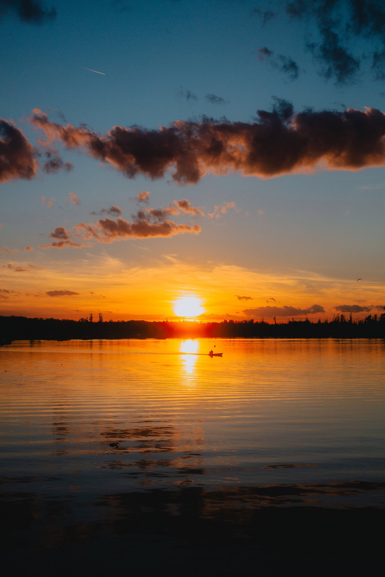 Vertikalt fotografi av en dramatisk solnedgang over en innsjø