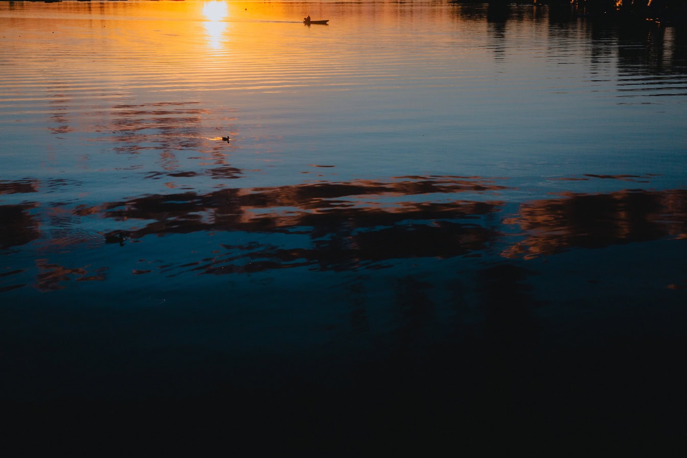 Ein Foto eines späten Sonnenuntergangs mit reflektierten Sonnenstrahlen auf der Oberfläche des Flusses