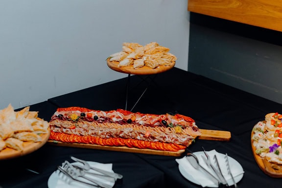 Tavolo con un piatto di torte e un vassoio di legno con una varietà di antipasti