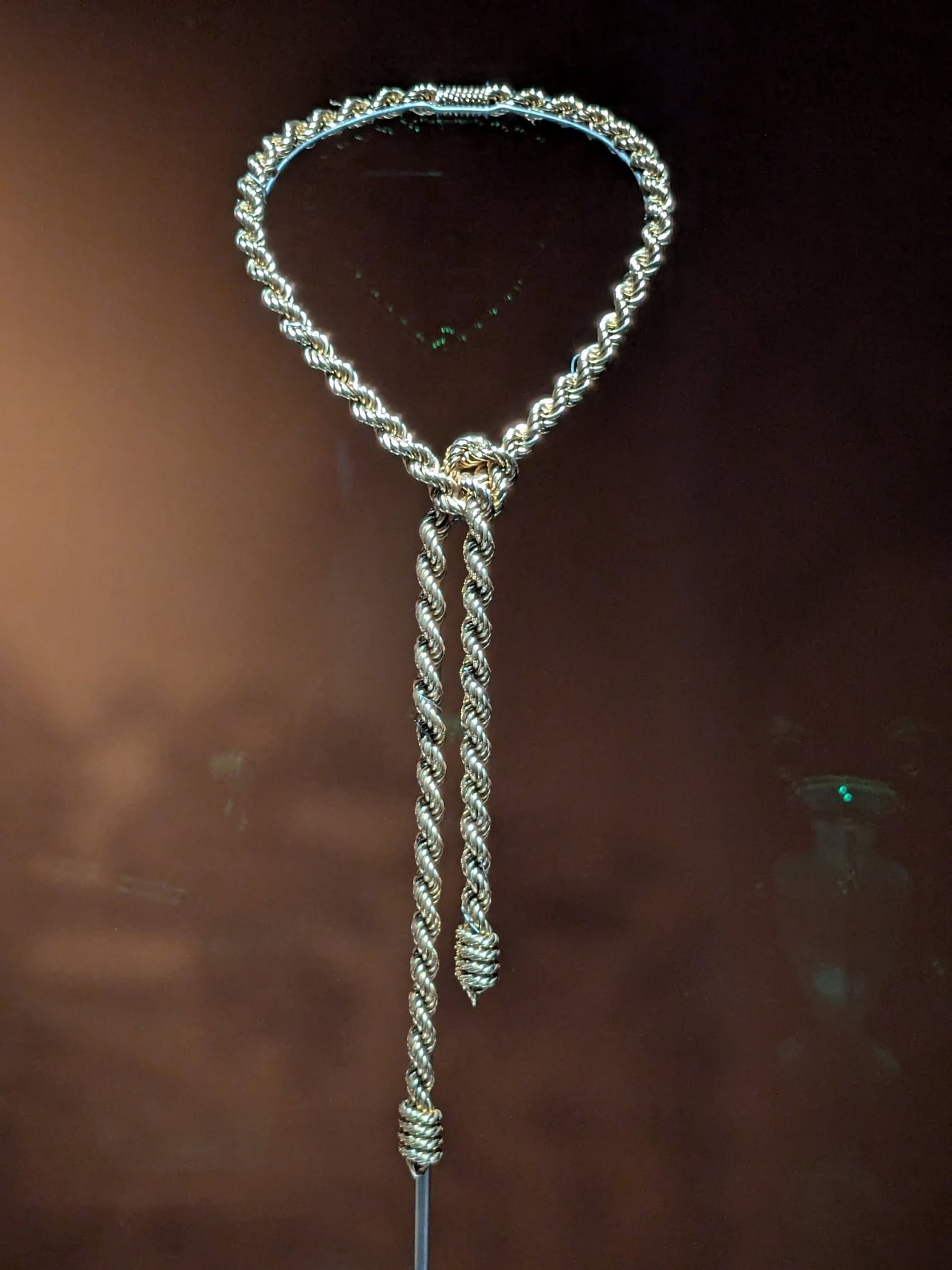 Zilveren halsband onder een glasoppervlak in museum