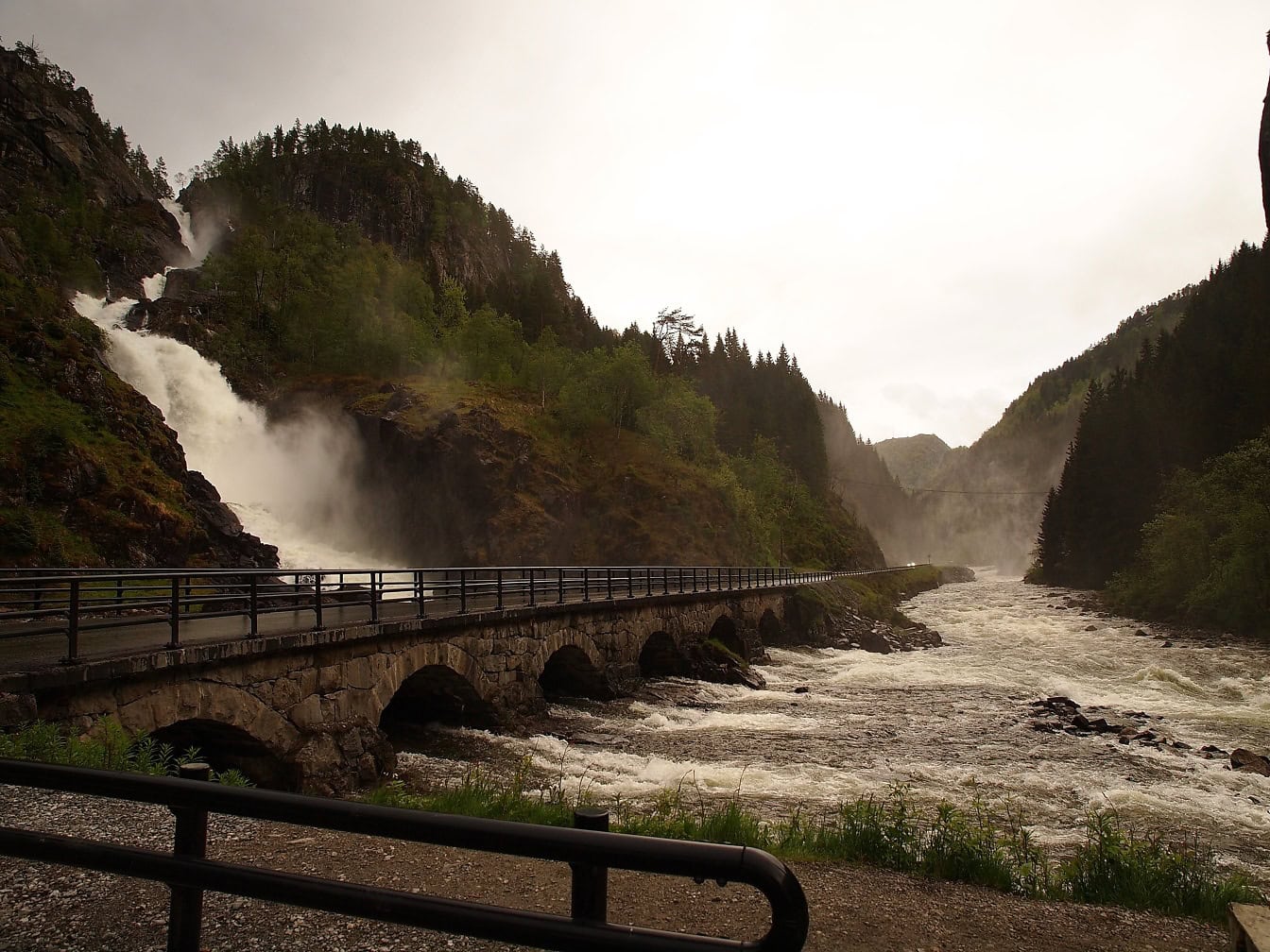 Puente de piedra sobre un río con las cascadas gemelas de Låtefossen o Låtefoss, condado de Vestland, Noruega