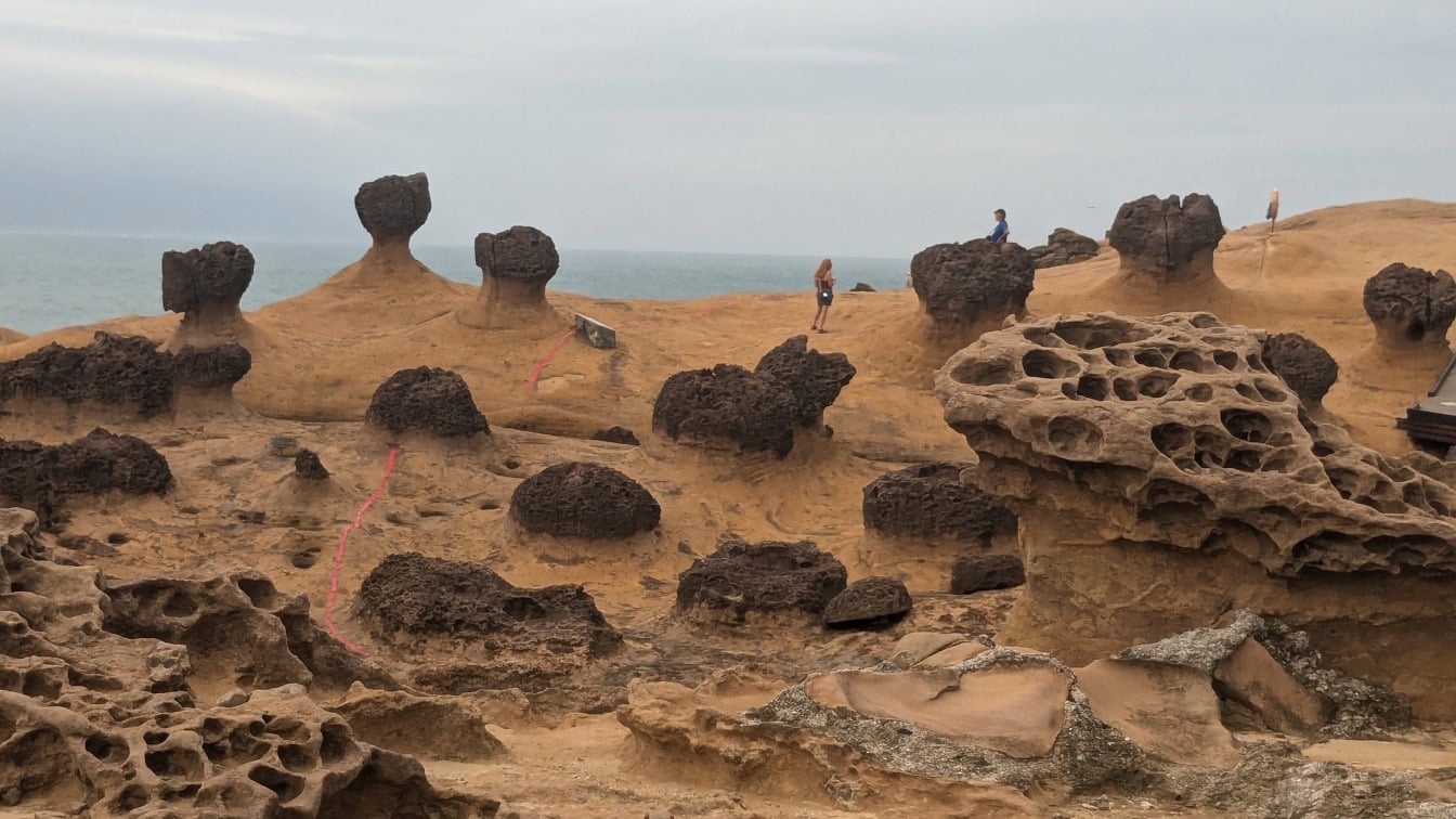 Panoramă de plajă de nisip cu formațiuni stâncoase de gresie făcute prin eroziune în geoparcul Yehliu, o capă sedimentară din districtul Wanli, New Taipei, Taiwan