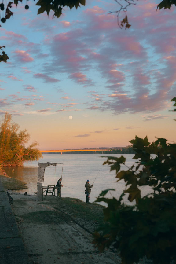 Hommes pêchant sur la rive d’un Danube avec des cannes à pêche