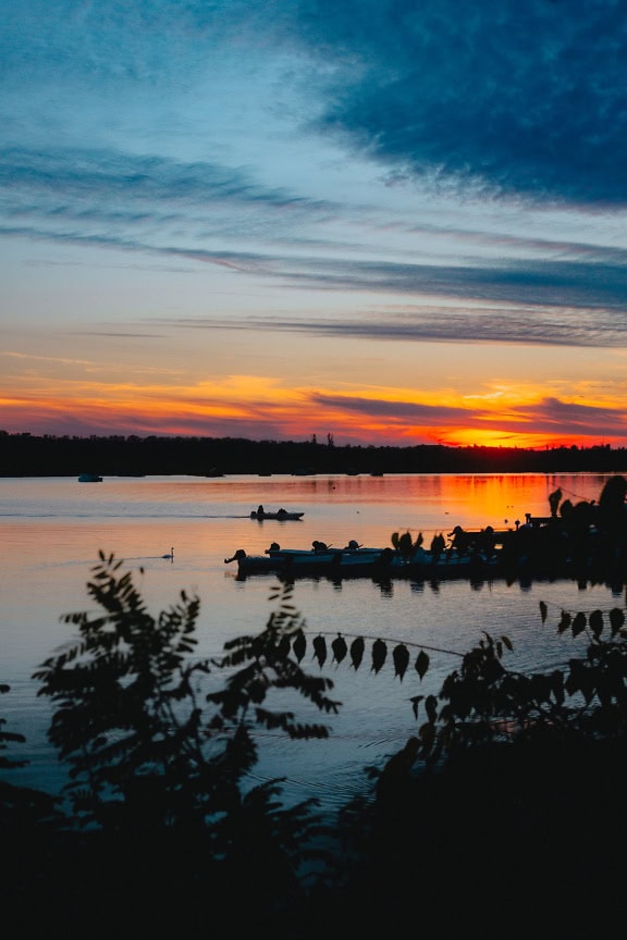 Silhouette di barche a motore da pesca su un lago durante il crepuscolo