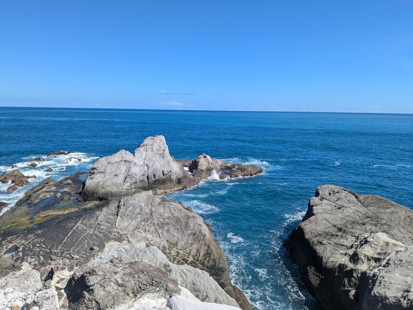 Sziklás strand kék vízzel és kék éggel Hualien közelében, Tajvan