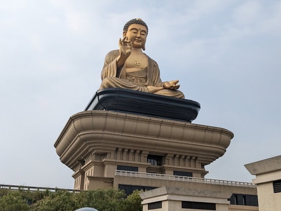 Large gold statue of a buddha on a pedestal at the Fo Guang Shan museum, a Buddhist cultural and religious memorial centre, Taiwan