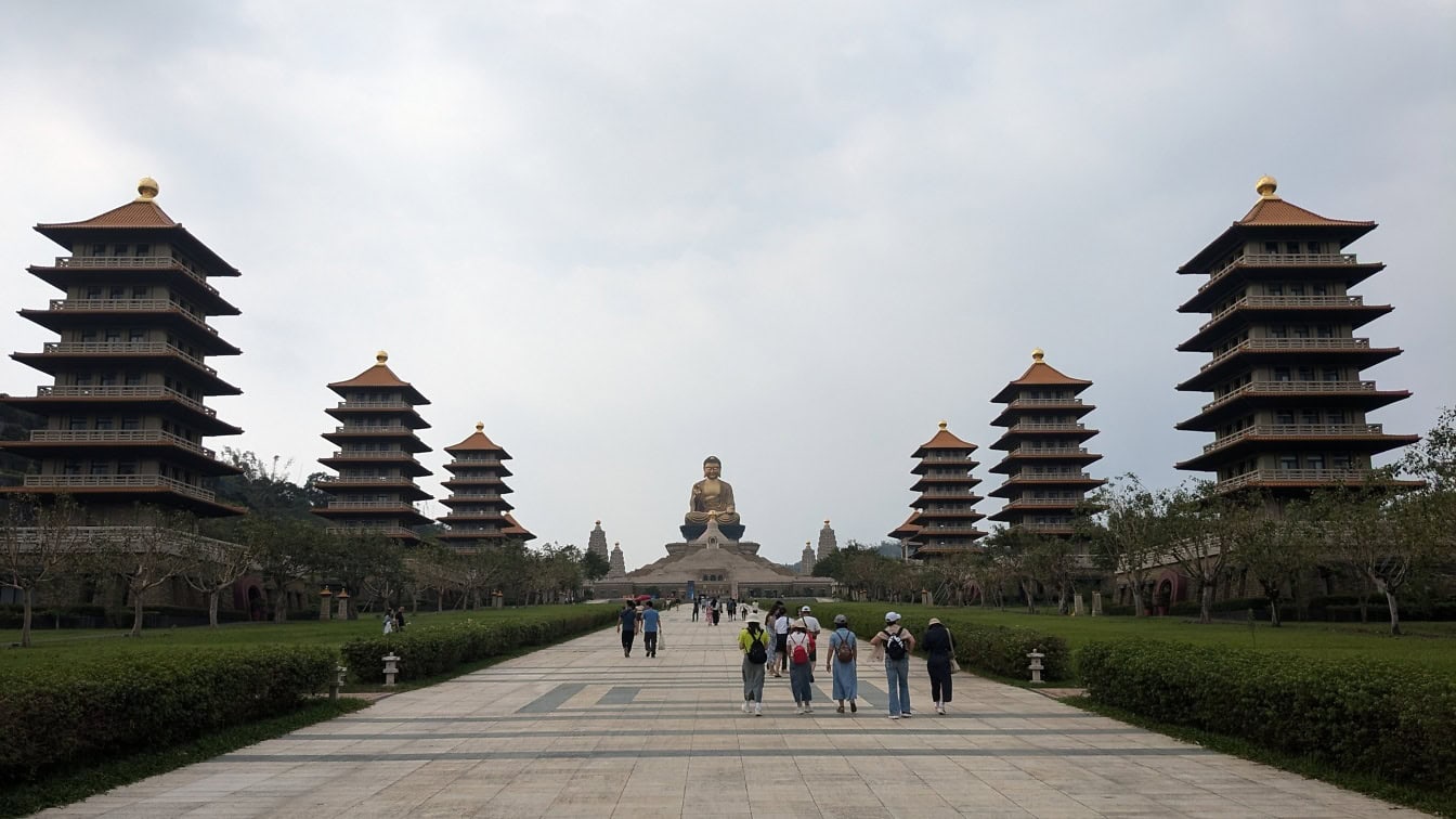 Emberek sétálnak egy ösvényen, háttérben egy nagy Buddha-szoborral a Fo Guang Shan Buddha múzeumban, Tajvanon