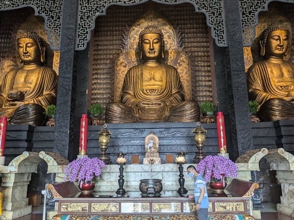 ประติมากรรมทองคําอันสง่างามของพระพุทธเจ้าสามองค์ที่ศาลเจ้าของอาราม Sangha Fo Guang Shan ซึ่งเป็นศูนย์จิตวิญญาณทางพุทธศาสนา