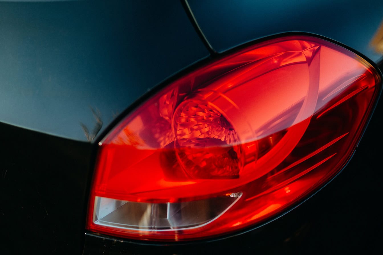 Primer plano del plástico rojo oscuro de la luz trasera de un coche negro