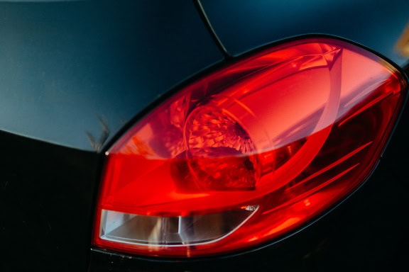 Primo piano della plastica rosso scuro del fanale posteriore di un’auto nera