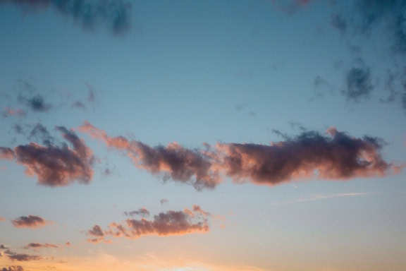 Sininen taivas pilvillä juuri ennen auringonlaskua ja auringonsäteet matalassa kulmassa