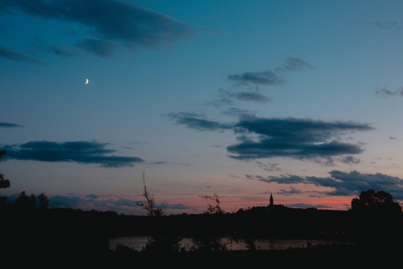 Natt over en innsjø med silhuett av tårn i det fjerne