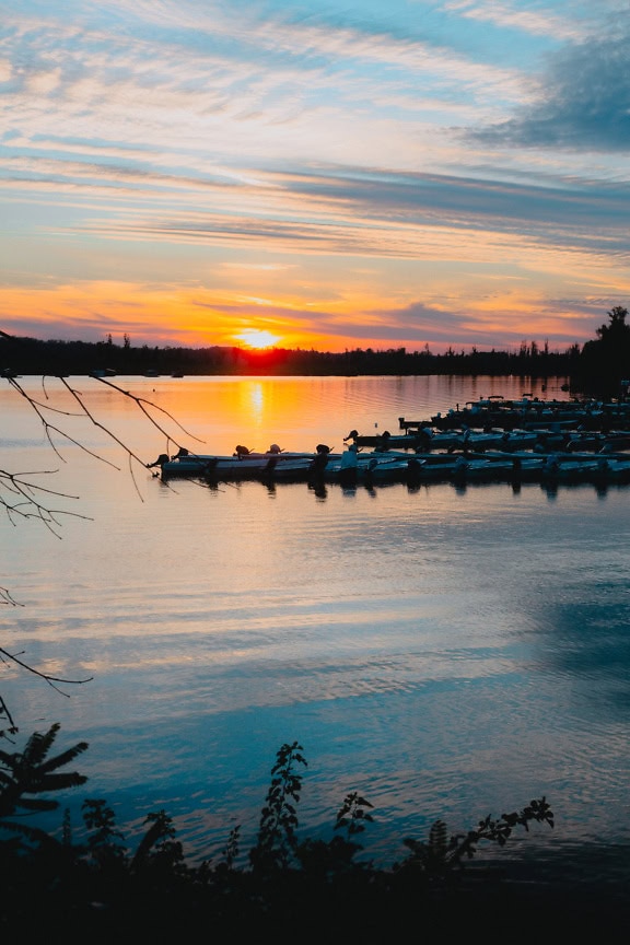 Small motor boats in the river port at dawn with the rising sun as a backlight