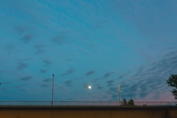 A bridge with a fence under the moonlight of the full moon in the sky