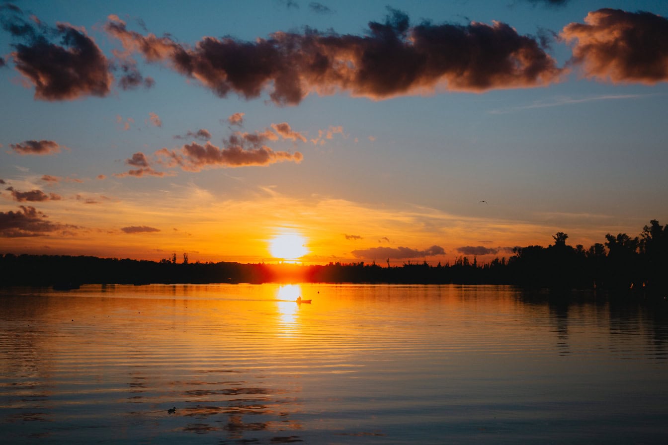 Oranssinkeltainen auringonlasku järven yllä