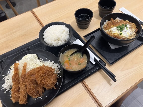 전통 아시아 요리인 돈까스 플래터로, 수프, 밥, 샐러드 및 기타 음식이 혼합된 조합으로 레스토랑의 테이블에 올려져 있습니다