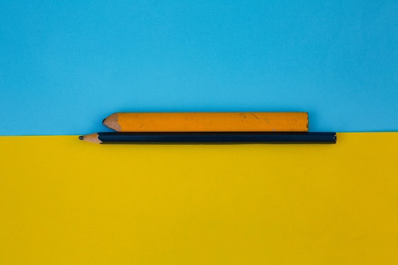 Black and orange pencil on a two-tone blue-yellow surface