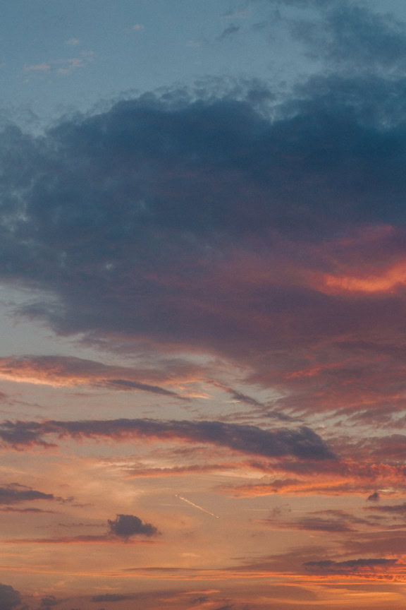 Bluish sky with grey clouds and and pinkish sunrays during dusk