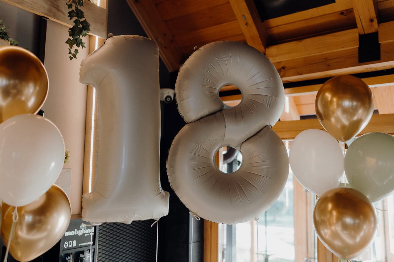 Grupo de globos de helio en forma de número dieciocho (18) como decoración en la fiesta de cumpleaños