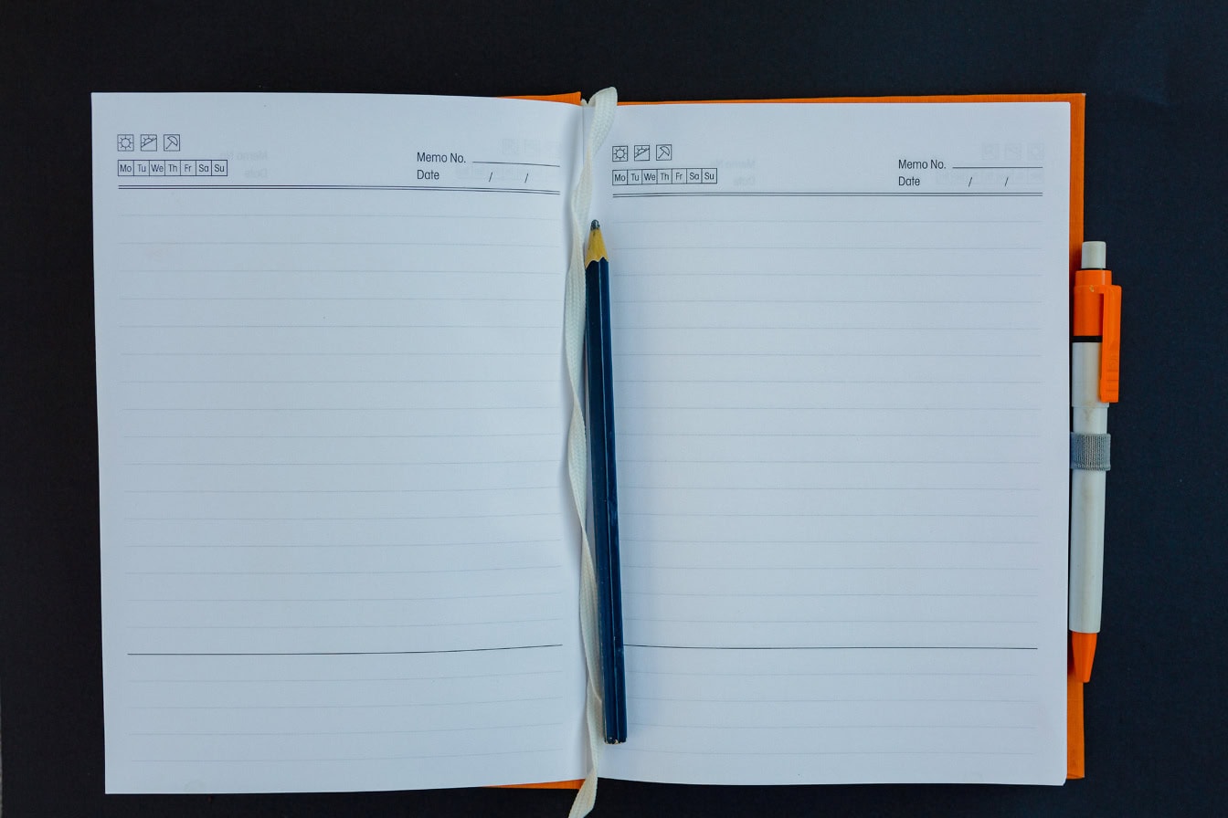 An opened notebook with a lead pencil on blank white pages and another pencil attached to a side of a notebook