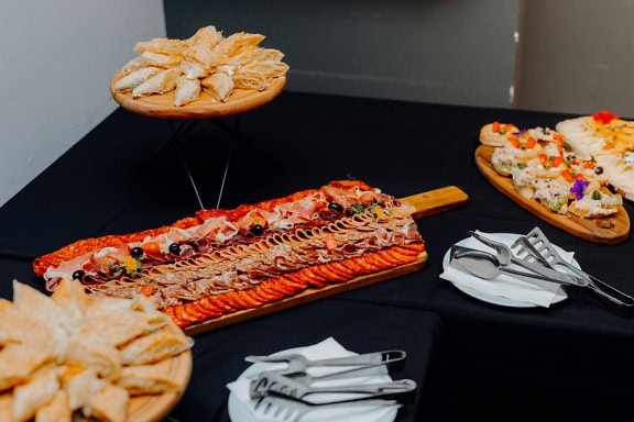 Table with plates of food with delicious appetizers, homemade pumpkin pie and sandwiches