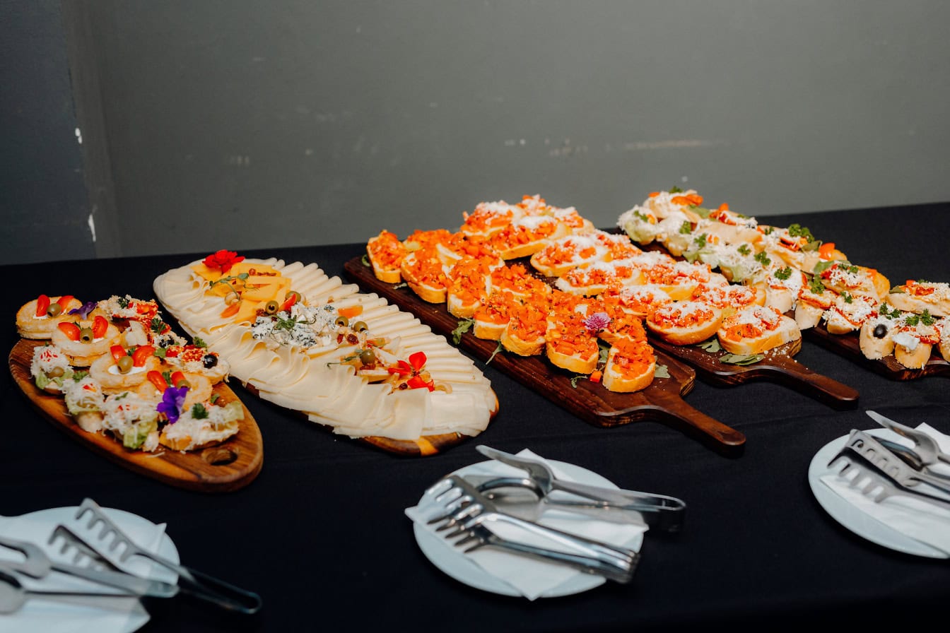 Table with plates with various appetizers, fast food snacks and sandwiches