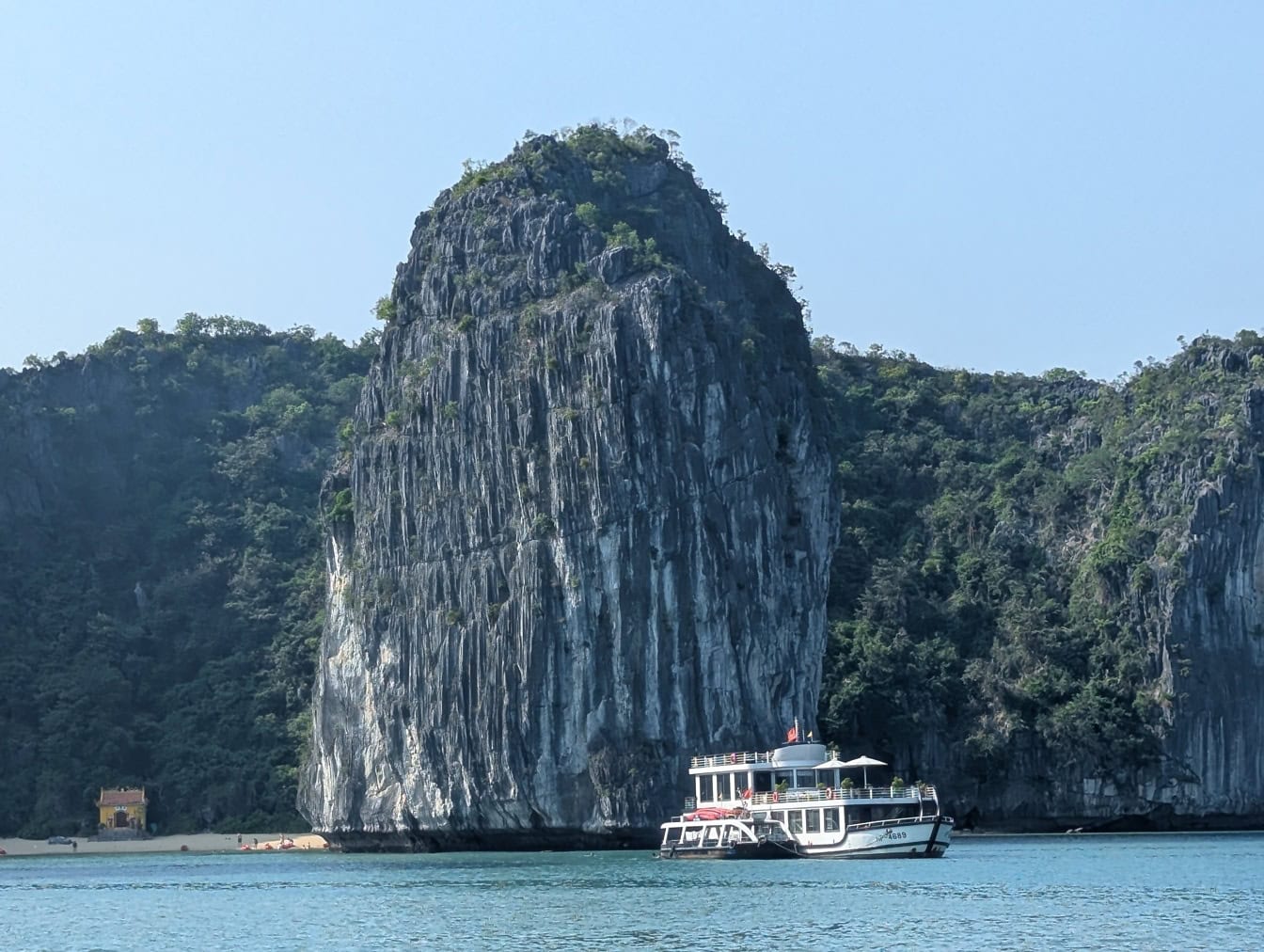 Výletní loď s turisty cestujícími mezi slavným skalním útvarem v zátoce Ha Long, Vietnam, Asie