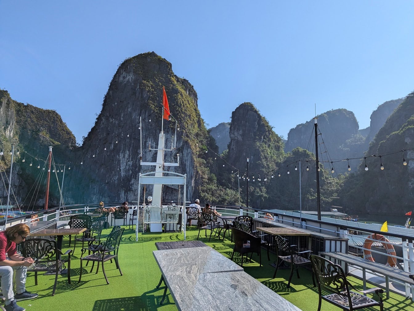 Pont d’un bateau de croisière touristique avec des tables et des chaises et un drapeau rouge dessus, île de Bo Hon, Vietnam